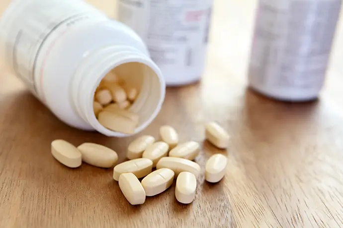A photo of nutritional supplement bottles and pills on a desktop surface